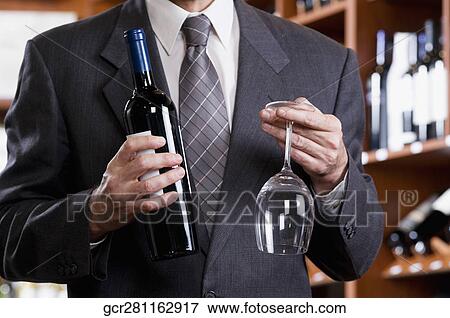 Businessman holding a wine bottle and a wine glass View Large Photo Image Stock Photo - Businessman holding a wine bottle and a wine glass. Fotosearch