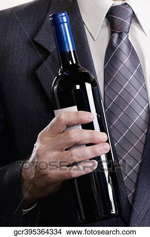 Businessman holding a wine bottle View Large Photo Image Picture - Businessman holding a wine bottle. Fotosearch