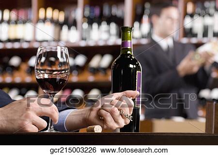 Businessman holding a wine glass and a corkscrew View Large Photo Image Stock Photograph - Businessman holding a wine glass and a corkscrew. Fotosearch