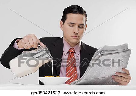 Businessman pouring milk into a bowl of cereal View Large Photo Image Stock Photo - Businessman pouring milk into a bowl of cereal. Fotosearch
