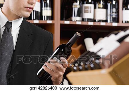 Businessman reading the label of a wine bottle View Large Photo Image Stock Photo - Businessman reading the label of a wine bottle. Fotosearch