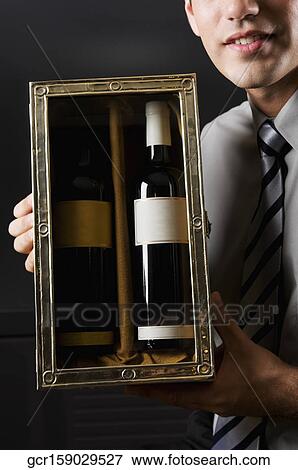 Stock Photo - Businessman showing a pair of wine bottles. Fotosearch