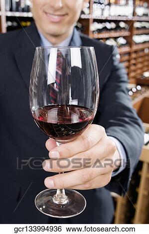 Stock Photograph - Businessman showing a wine glass in a bar. Fotosearch