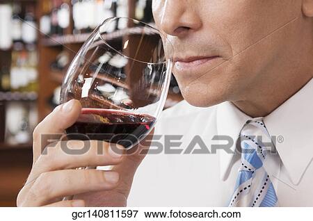Stock Photo - Businessman smelling red wine in a bar. Fotosearch