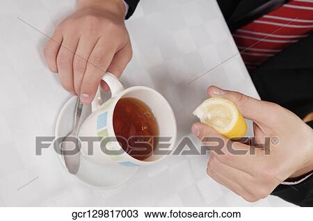 Businessman squeezing lemon into tea View Large Photo Image Stock Image - Businessman squeezing lemon into tea. Fotosearch