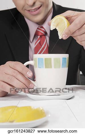 Stock Photo - Businessman squeezing lemon into tea. Fotosearch
