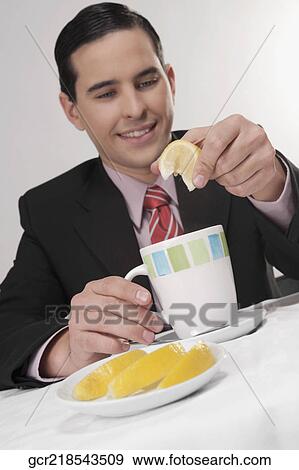 Businessman squeezing lemon into tea View Large Photo Image Stock Photo - Businessman squeezing lemon into tea. Fotosearch