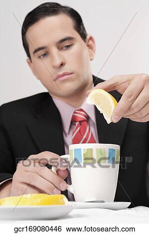 Businessman squeezing lemon into tea View Large Photo Image Stock Photograph - Businessman squeezing lemon into tea. Fotosearch