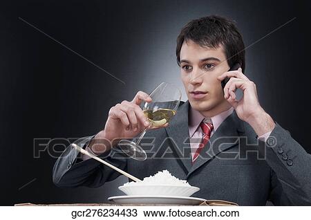 Businessman talking on a mobile phone while eating View Large Photo Image Stock Image - Businessman talking on a mobile phone while eating. Fotosearch