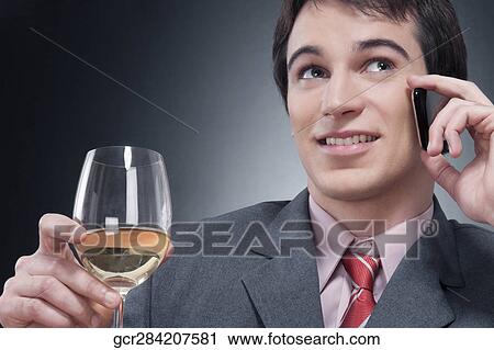 Businessman talking on a mobile phone and drinking wine View Large Photo Image Stock Image - Businessman talking on a mobile phone and drinking wine. Fotosearch