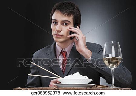 Businessman talking on a mobile phone while eating View Large Photo Image Stock Photo - Businessman talking on a mobile phone while eating. Fotosearch