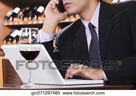 Businessman talking on a mobile phone in a bar View Large Photo Image Stock Photography - Businessman talking on a mobile phone in a bar. Fotosearch