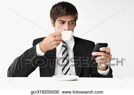 Businessman using a mobile phone and drinking coffee View Large Photo Image Stock Image - Businessman using a mobile phone and drinking coffee. Fotosearch