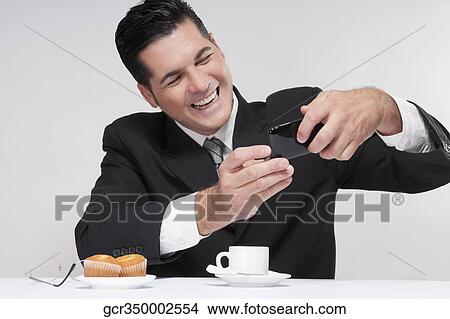 Picture - Businessman using a mobile phone over a cup of coffee. Fotosearch