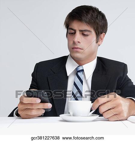 Stock Photo - Businessman using a mobile phone over a cup of coffee. Fotosearch