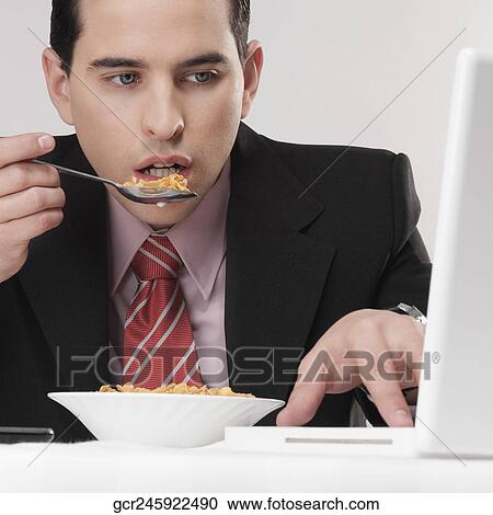 Businessman working on a laptop at breakfast table View Large Photo Image Stock Image - Businessman working on a laptop at breakfast table. Fotosearch