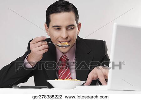Businessman working on a laptop at breakfast table View Large Photo Image Stock Image - Businessman working on a laptop at breakfast table. Fotosearch