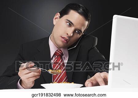 Stock Photo - Businessman working on a laptop at breakfast table. Fotosearch