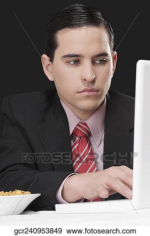 Stock Photo - Businessman working on a laptop at breakfast table. Fotosearch