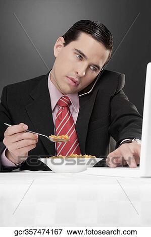 Businessman working on a laptop at breakfast table View Large Photo Image Stock Photo - Businessman working on a laptop at breakfast table. Fotosearch