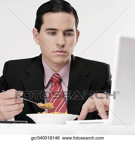 Businessman working on a laptop at breakfast table View Large Photo Image Stock Photograph - Businessman working on a laptop at breakfast table. Fotosearch