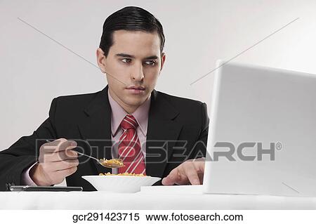 Businessman working on a laptop at breakfast table View Large Photo Image Stock Photography - Businessman working on a laptop at breakfast table. Fotosearch