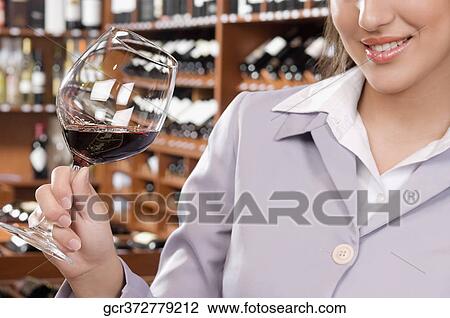 Businesswoman holding a glass of wine in a bar and smiling View Large Photo Image Stock Image - Businesswoman holding a glass of wine in a bar and smiling. Fotosearch