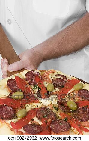 Chef holding a pizza on a pizza peel View Large Photo Image Stock Image - Chef holding a pizza on a pizza peel. Fotosearch
