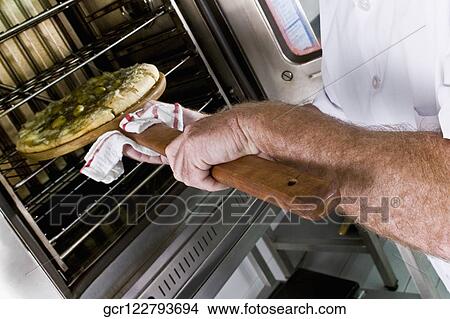 Chef putting a pizza into an oven View Large Photo Image Picture - Chef putting a pizza into an oven. Fotosearch