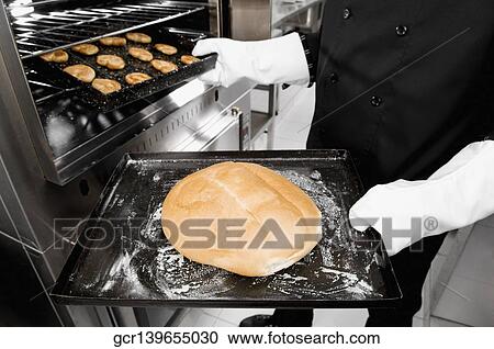 Chef taking out a bun and cookies from an oven View Large Photo Image Stock Image - Chef taking out a bun and cookies from an oven. Fotosearch