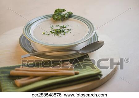 Stock Photograph - Close-up of a bowl of soup served with breadsticks. Fotosearch