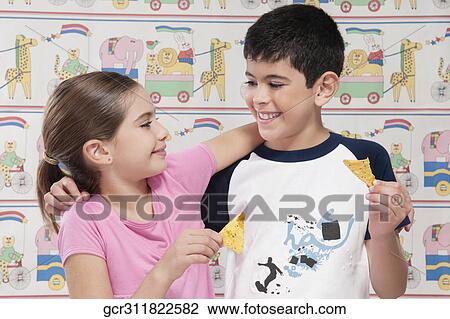 Stock Image - Close-up of a boy and a girl eating nachos. Fotosearch