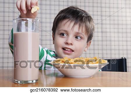 Close-up of a boy dropping corn flakes into a glass of chocolate milkshake View Large Photo Image Stock Image - Close-up of a boy dropping corn flakes into a glass of chocolate milkshake. Fotosearch