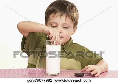 Close-up of a boy dunking cookies into milk View Large Photo Image Stock Image - Close-up of a boy dunking cookies into milk. Fotosearch