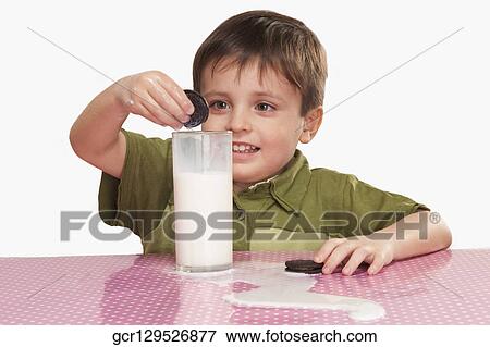 Close-up of a boy dunking cookies into milk View Large Photo Image Stock Photo - Close-up of a boy dunking cookies into milk. Fotosearch