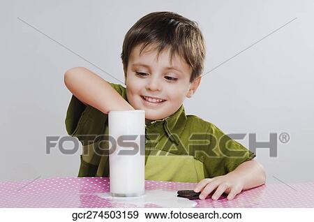Close-up of a boy dunking cookies into milk View Large Photo Image Stock Photo - Close-up of a boy dunking cookies into milk. Fotosearch