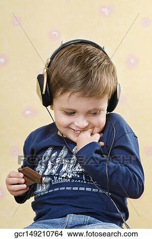 Close-up of a boy eating chocolate and listening to music View Large Photo Image Picture - Close-up of a boy eating chocolate and listening to music. Fotosearch