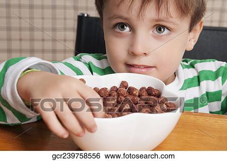 Close-up of a boy eating dry cereal View Large Photo Image Stock Photograph - Close-up of a boy eating dry cereal. Fotosearch