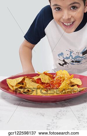 Close-up of a boy looking at a platter of nachos View Large Photo Image Stock Photo - Close-up of a boy looking at a platter of nachos. Fotosearch