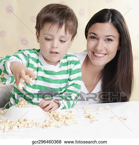 Close-up of a boy playing with popcorns beside his mother View Large Photo Image Stock Photo - Close-up of a boy playing with popcorns beside his mother. Fotosearch