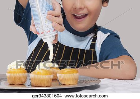 Close-up of a boy putting whipped cream on cupcakes View Large Photo Image Picture - Close-up of a boy putting whipped cream on cupcakes. Fotosearch
