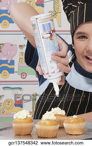 Close-up of a boy putting whipped cream on cupcakes View Large Photo Image Stock Image - Close-up of a boy putting whipped cream on cupcakes. Fotosearch