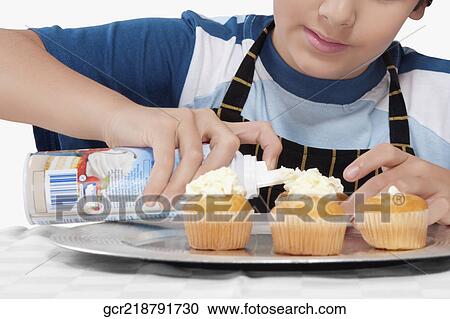 Close-up of a boy putting whipped cream on cupcakes View Large Photo Image Stock Image - Close-up of a boy putting whipped cream on cupcakes. Fotosearch