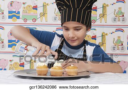 Close-up of a boy putting whipped cream on cupcakes View Large Photo Image Stock Photograph - Close-up of a boy putting whipped cream on cupcakes. Fotosearch