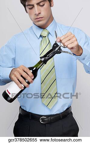 Stock Photography - Close-up of a businessman opening a bottle of wine. Fotosearch
