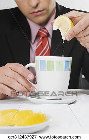 Close-up of a businessman squeezing lemon into a cup View Large Photo Image Stock Photo - Close-up of a businessman squeezing lemon into a cup. Fotosearch