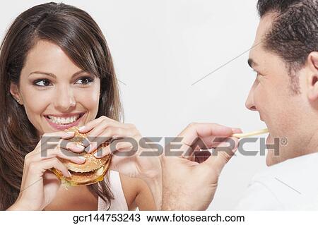 Close-up of a couple eating hamburgers and french fries View Large Photo Image Stock Image - Close-up of a couple eating hamburgers and french fries. Fotosearch