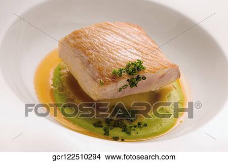Picture - Close-up of a fish steak on a bed of sauce. Fotosearch
