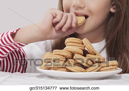 Close-up of a girl eating a cookie View Large Photo Image Stock Photo - Close-up of a girl eating a cookie. Fotosearch