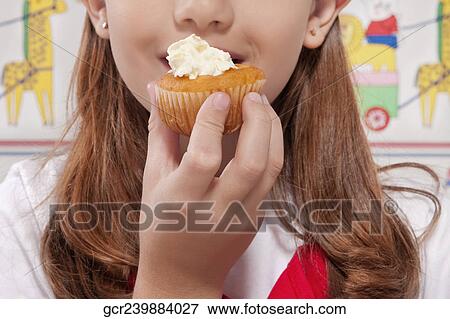 Close-up of a girl eating a cupcake View Large Photo Image Stock Photo - Close-up of a girl eating a cupcake. Fotosearch